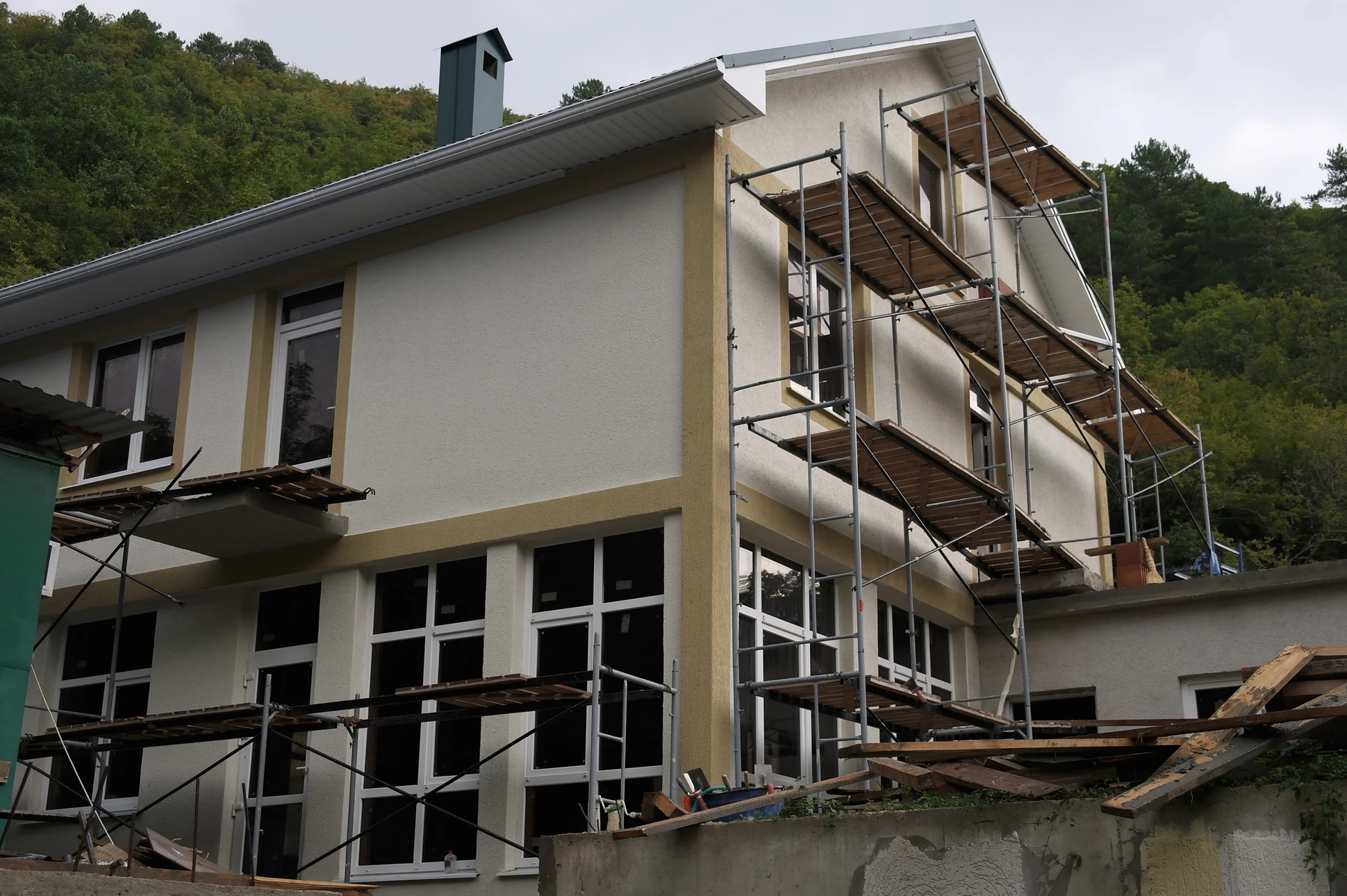 Chantier de rénovation extérieure d'une maison individuelle avec échafaudage métallique tubulaire installé sur la façade