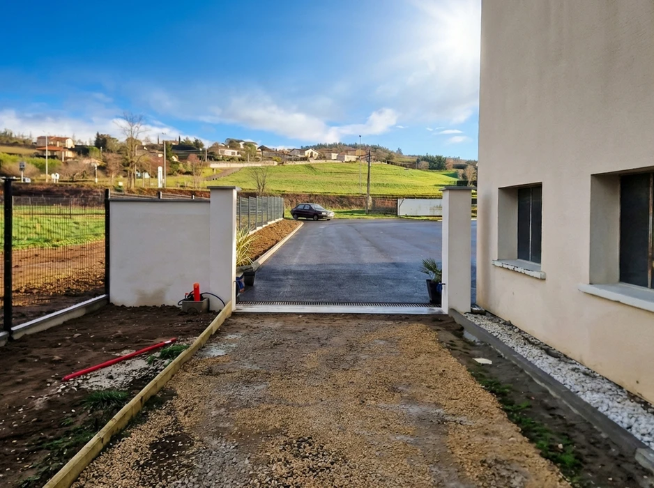 Portail coulissant motorisé en cours d'installation, entre deux piliers en béton enduit blanc