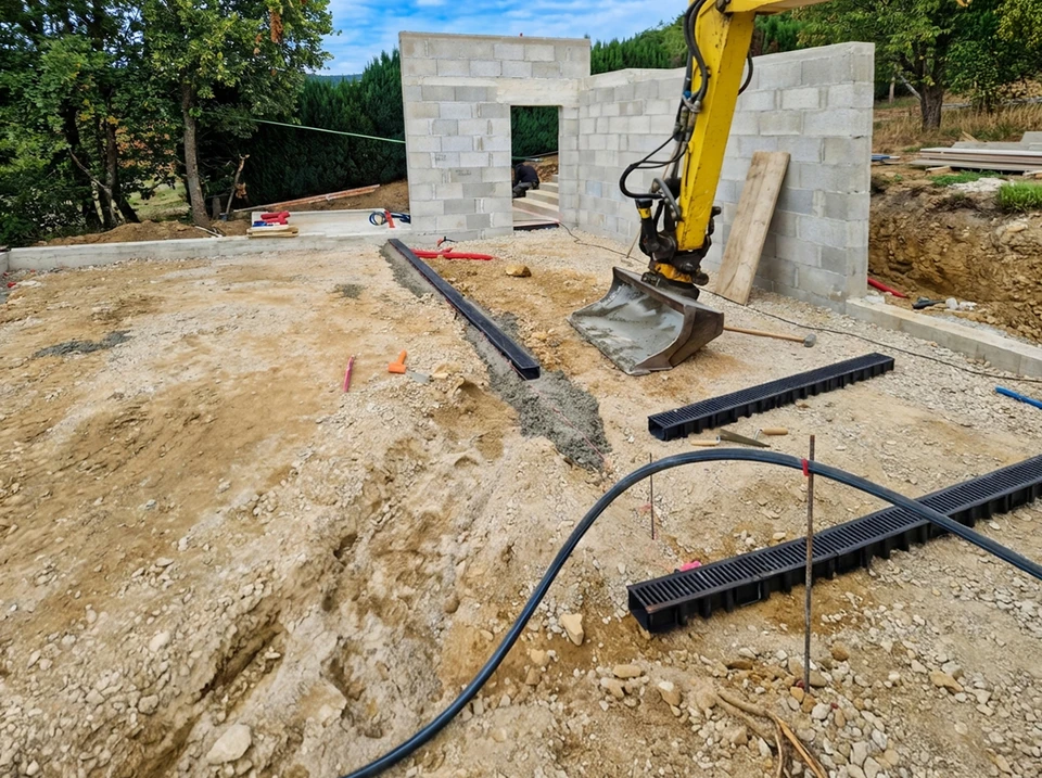 Chantier de terrassement en extérieur avec pelleteuse hydraulique jaune en action sur terrain sablonneux sous ciel bleu nuageux